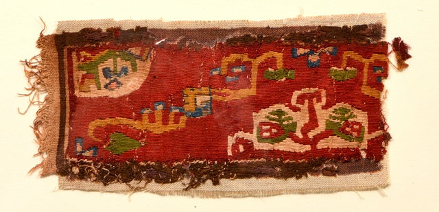 Appraisal: A RECTANGULAR FRAGMENT polychrome hooked design on a deep red