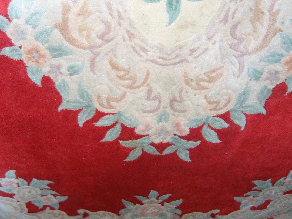 Appraisal: A red ground Chinese wool carpet with floral medallion decoration