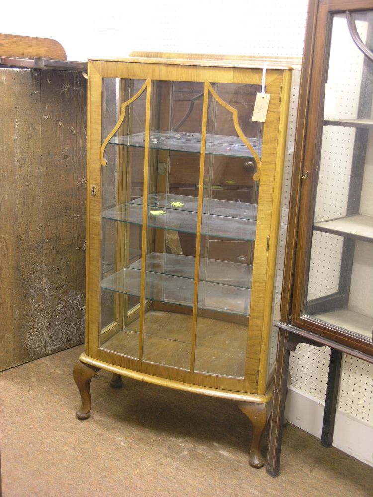 Appraisal: A walnut bow fronted display cabinet enclosed by single door