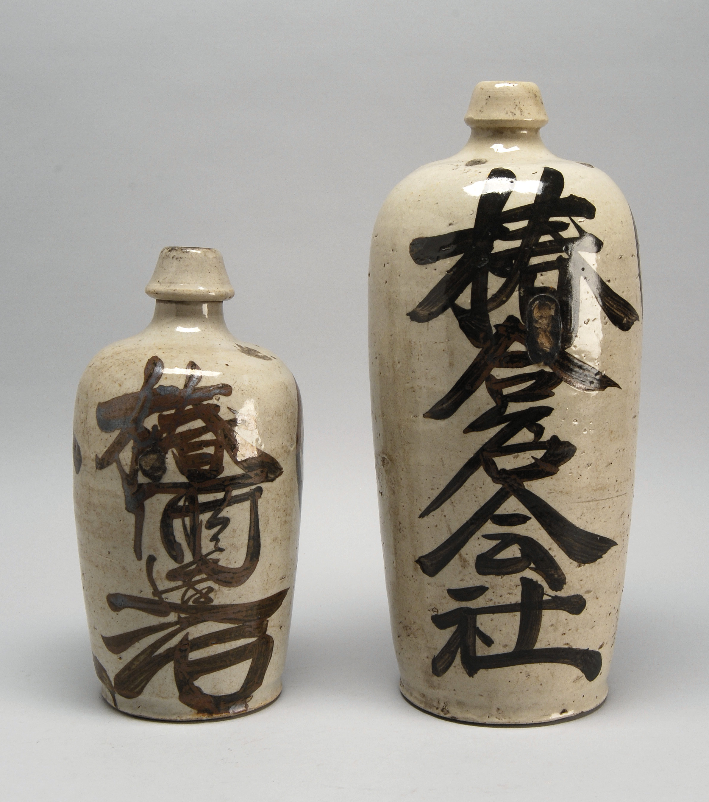 Appraisal: TWO STONEWARE SAKE BOTTLES Early th CenturyBoth with calligraphic decoration