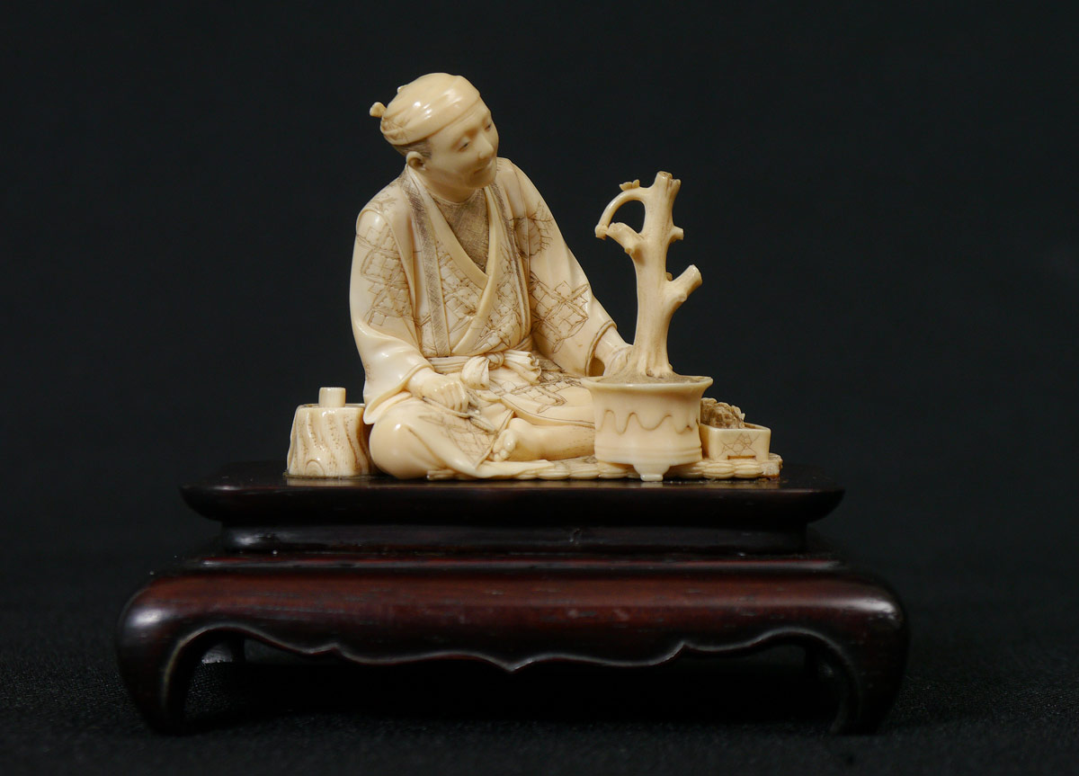 Appraisal: MAN TENDING BONSAI IVORY GROUPING Figure of a seated man