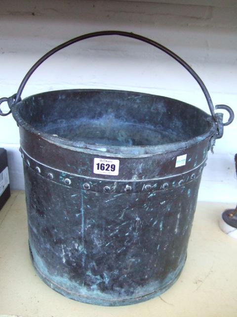 Appraisal: A copper riveted bucket with cast iron swing over handle