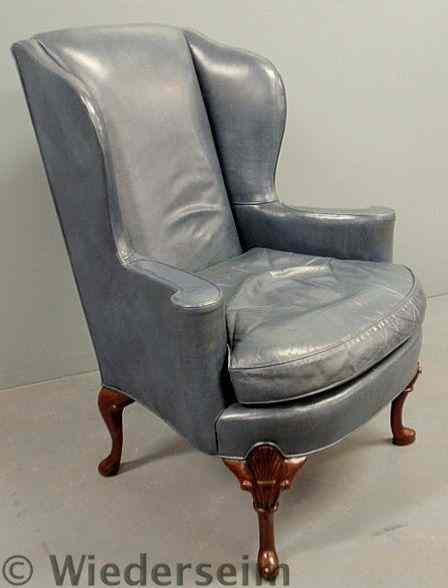 Appraisal: Queen Anne style blue leather wing chair with carved mahogany