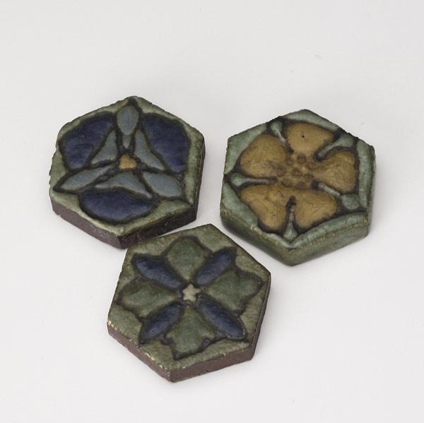 Appraisal: GRUEBY Three rare hexagonal tiles each with floral decoration Each