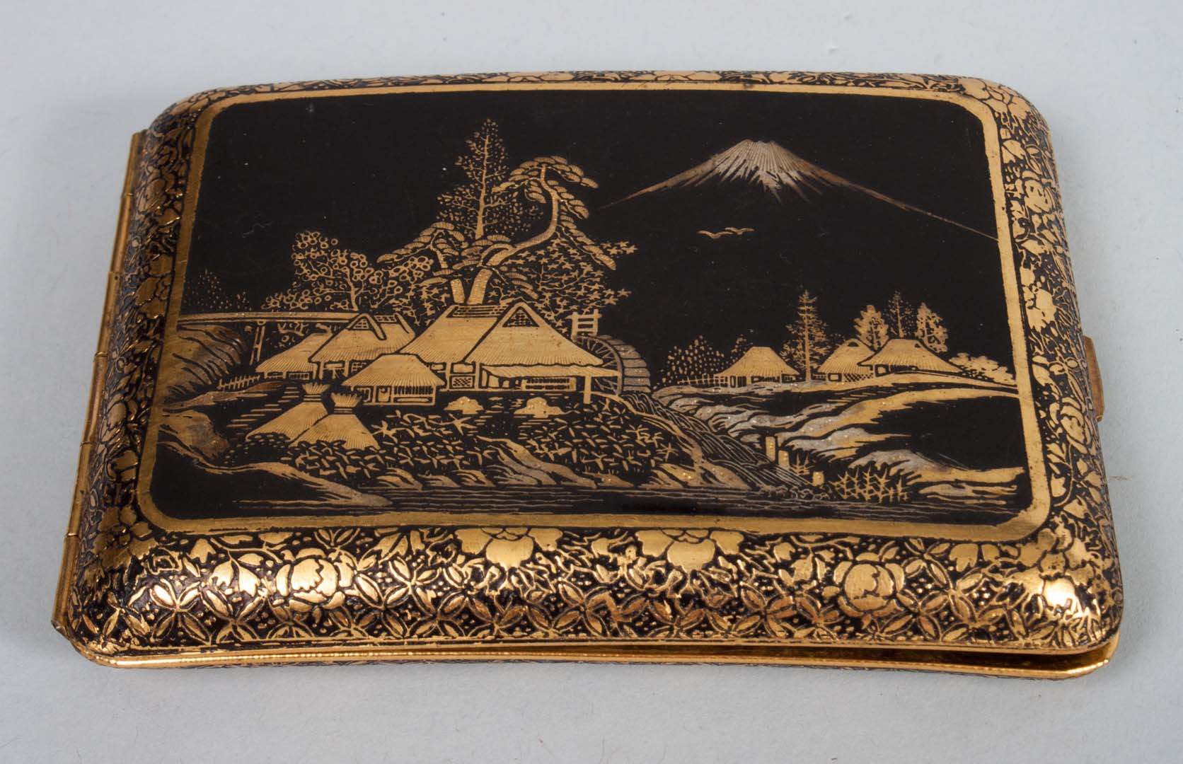 Appraisal: Japanese gilt-metal cigarette case cover depicting village with Mount Fuji