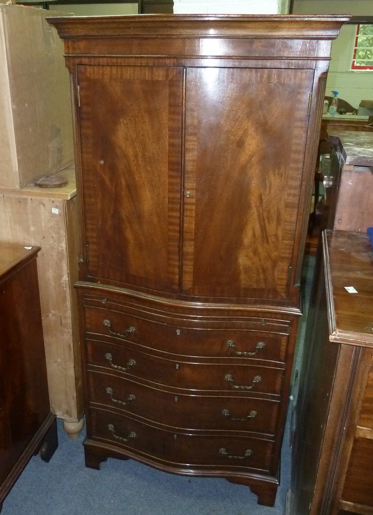 Appraisal: A mahogany serpentine front cupboard enclosed by a pair of