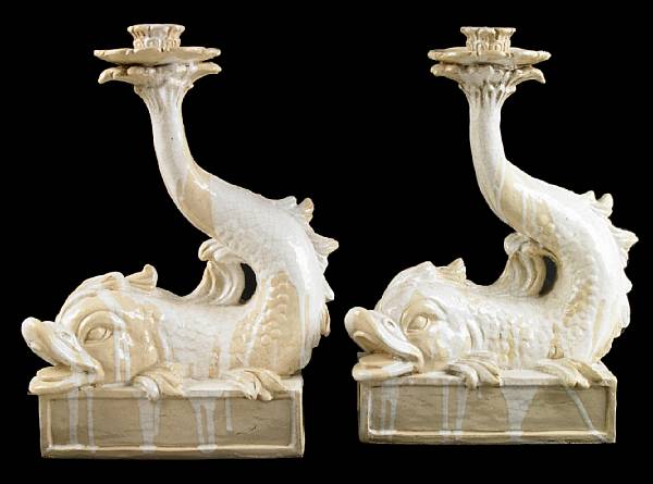 Appraisal: A pair of Italian glazed earthenware dolphin form candlesticks height