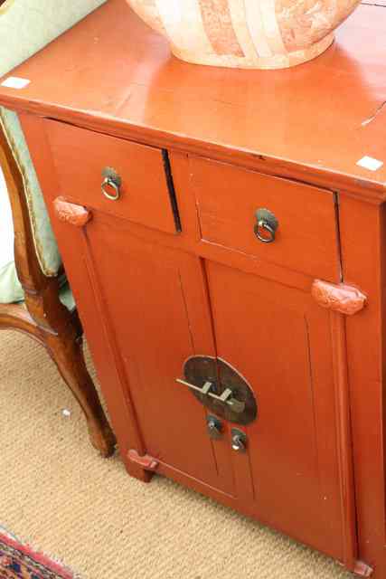 Appraisal: AN ORIENTAL RED LACQUERED SIDE CABINET with two drawers and