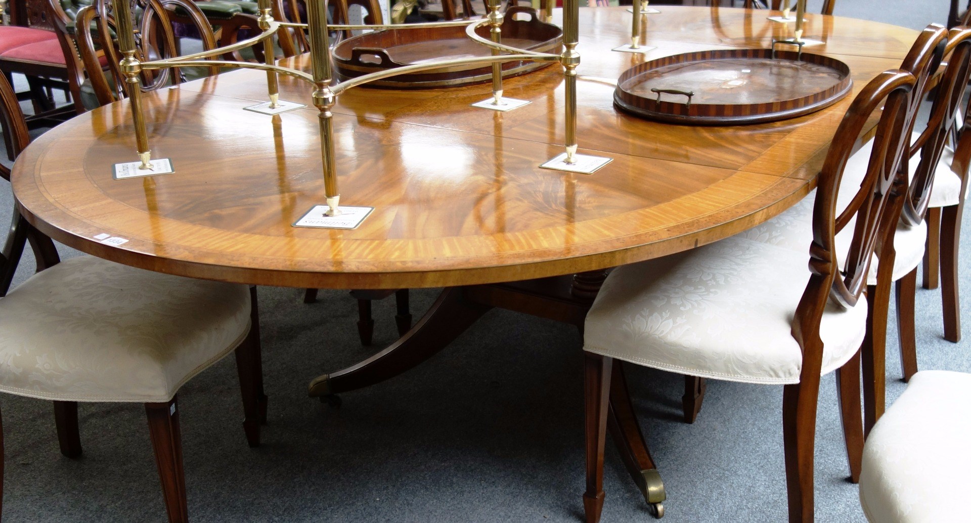 Appraisal: A satinwood and pollard oak banded mahogany extending circular dining