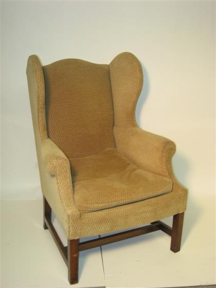 Appraisal: Beige upholstered wingback armchair With square legs and stretcher H