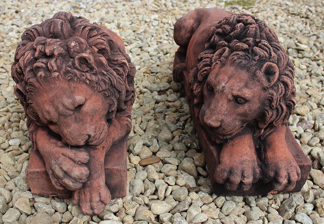 Appraisal: A PAIR OF TERRACOTTA COLOURED CAST COMPOSITE LIONS on rectangular