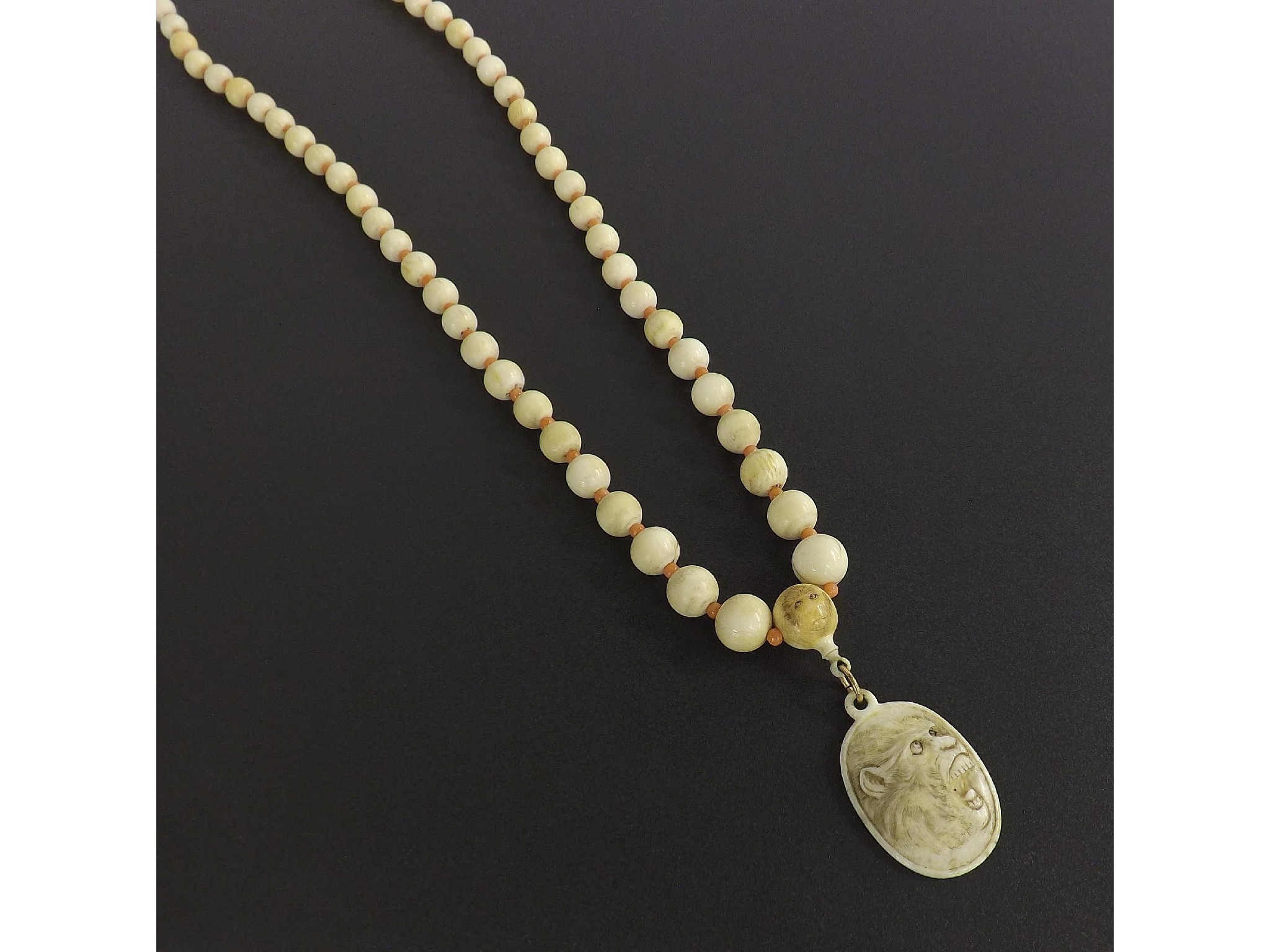 Appraisal: Ivory necklace interspersed with coral the largest bead carved with