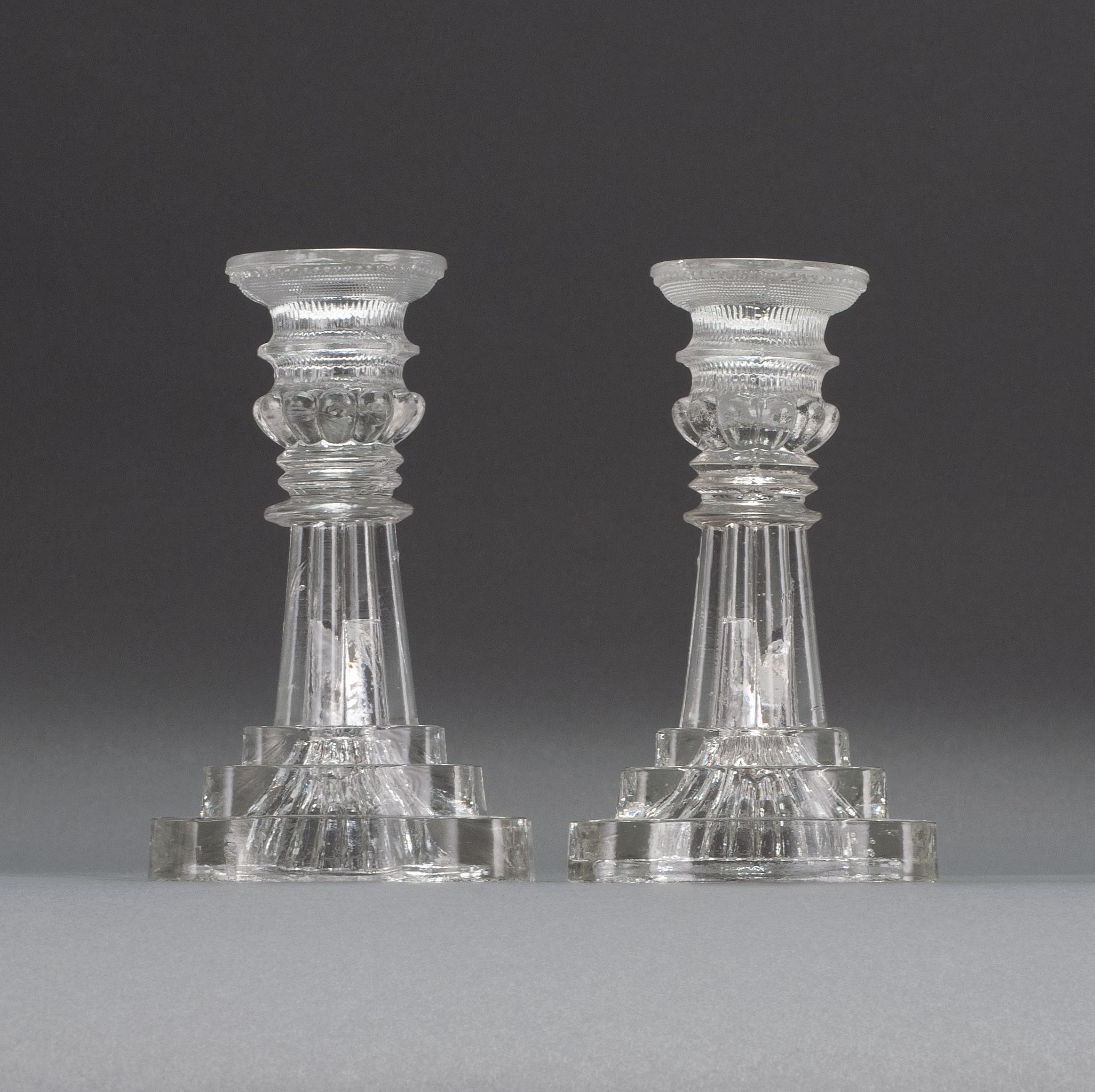 Appraisal: PAIR OF SANDWICH GLASS COMPANY CLEAR GLASS CANDLESTICKS Second Quarter