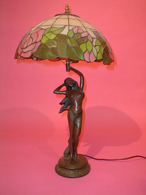 Appraisal: A scantily clad female supporting a Tiffany style rose lamp