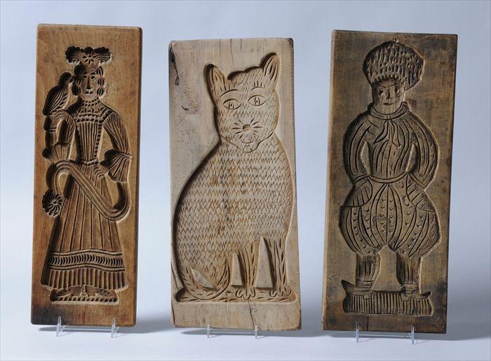 Appraisal: THREE CARVED WOOD CAKE BOARDS With figures of a cat