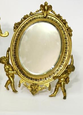 Appraisal: A GILDED METAL STRUT MIRROR of oval form the moulded