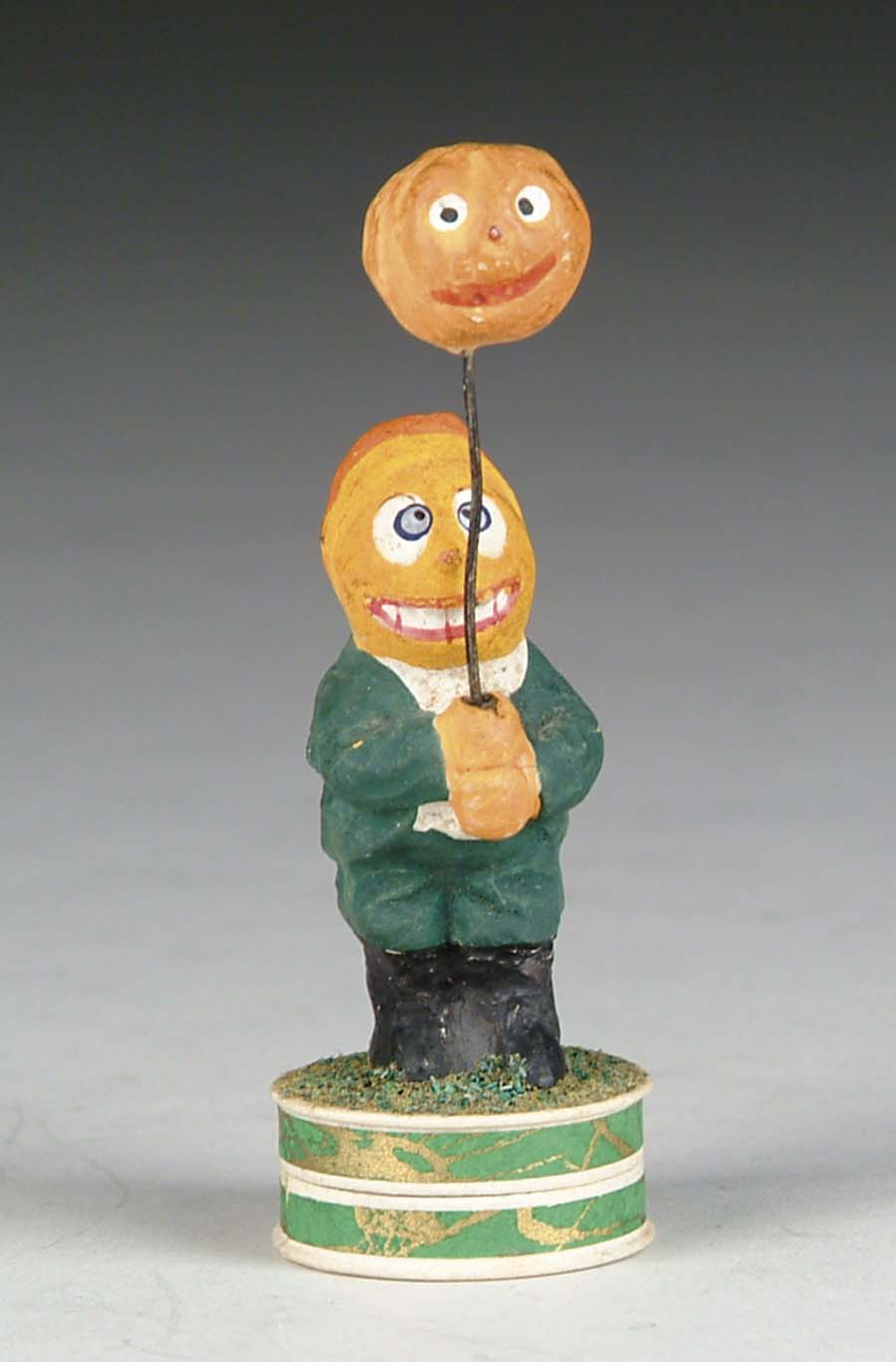 Appraisal: MINIATURE FIGURAL CANDY CONTAINER Composition pumpkin-head boy holding balloon-like jack-o-lantern