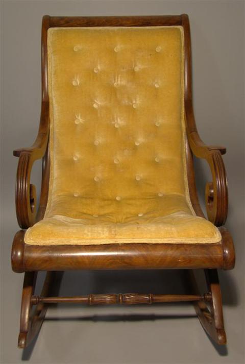 Appraisal: EMPIRE MAHOGANY ROCKER The buttoned velvet upholstery flanked by slightly