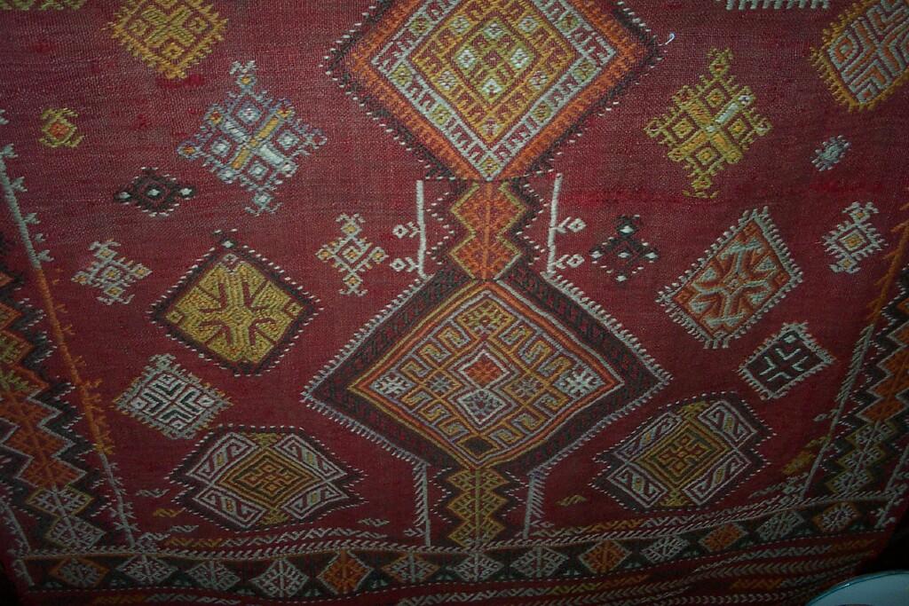 Appraisal: An Eastern red ground rug with embroidered geometric decoration in