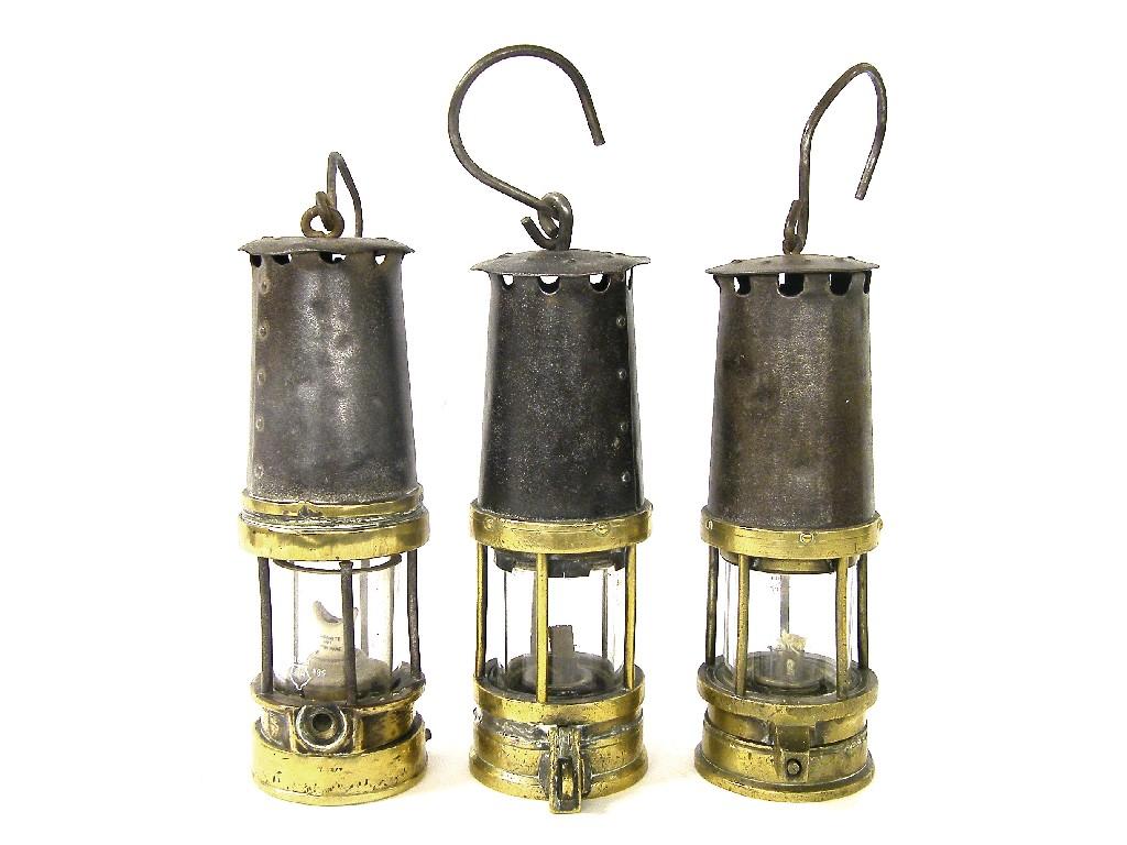 Appraisal: Three similar brass and iron miner's lamps high approx without