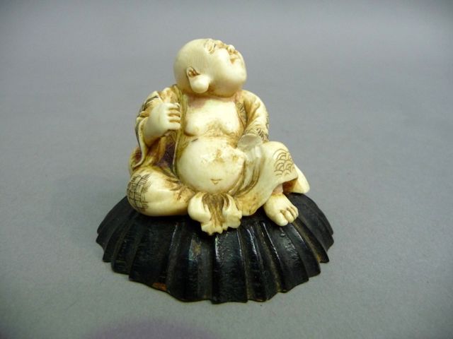 Appraisal: A Japanese carved ivory netsuke of a seated man some