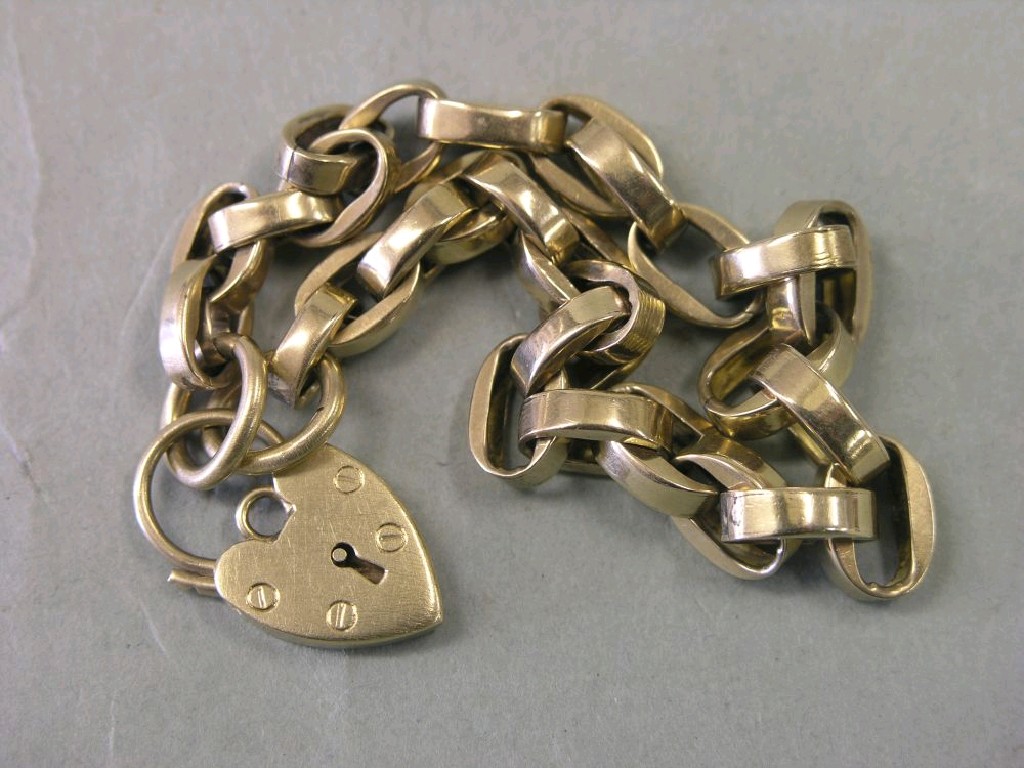 Appraisal: A yellow metal link bracelet with heart-shape padlock pendant unmarked