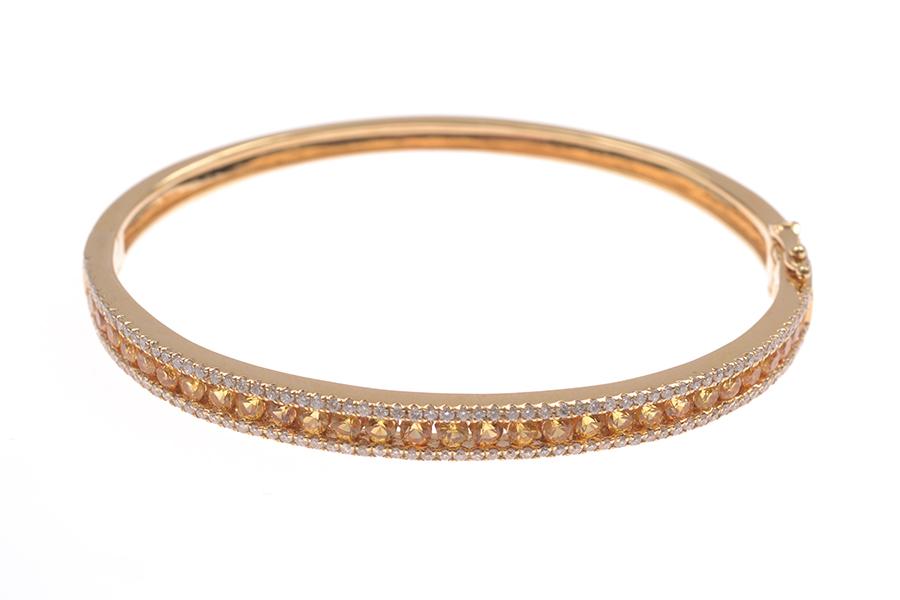 Appraisal: A YELLOW SAPPHIRE AND DIAMOND HINGED BANGLE IN CT GOLD