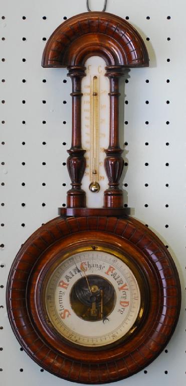 Appraisal: EDWARDIAN WALNUT ANEROID BAROMETER AND THERMOMETER the carved circular case