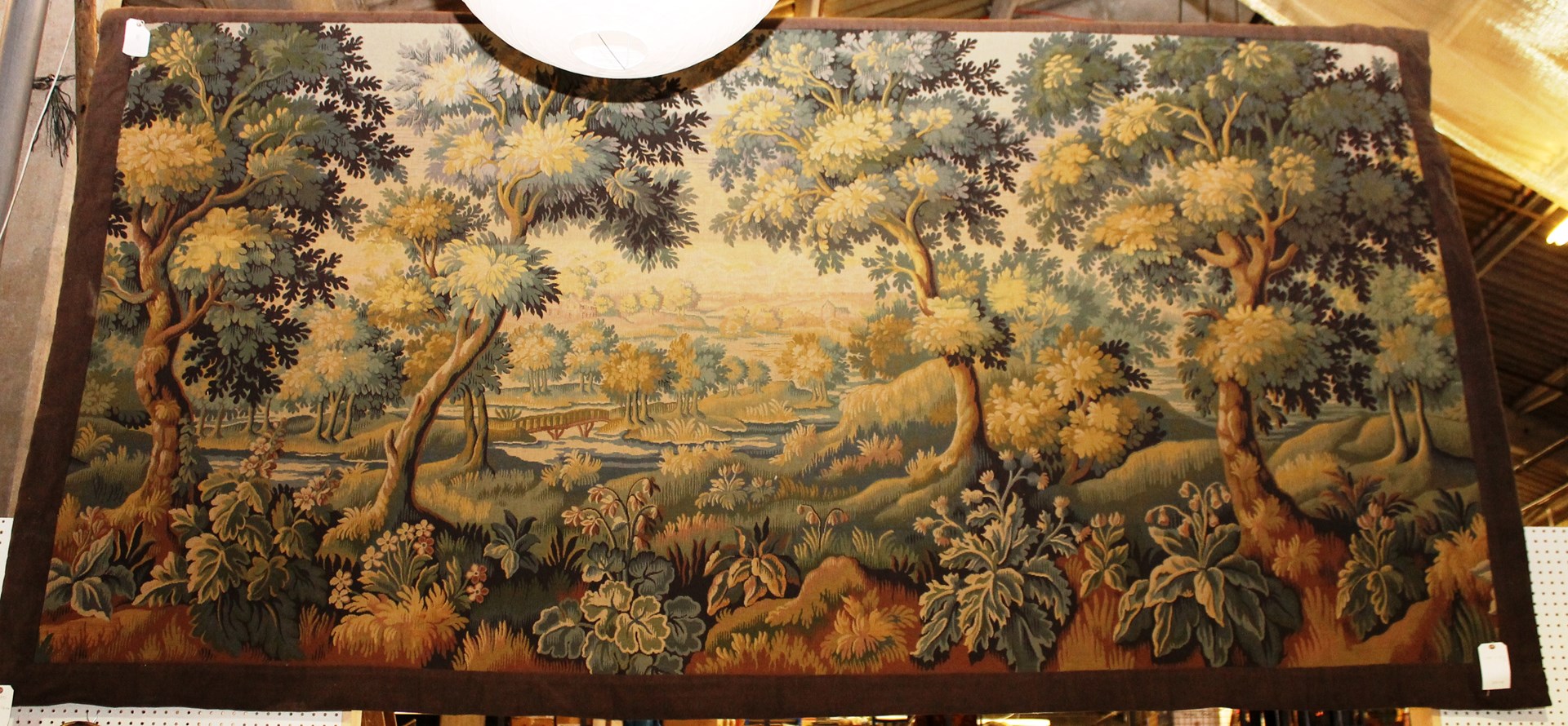 Appraisal: A machine made tapestry panel with a wooded landscape lake