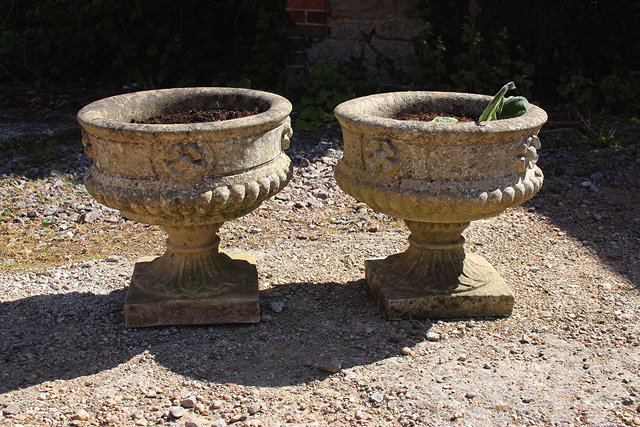 Appraisal: A PAIR OF RECONSTITUTED STONE URNS with rose decoration and