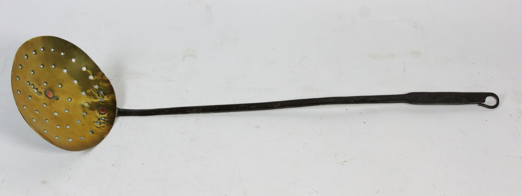 Appraisal: A pierced brass skimmer with iron handle and hanging loop