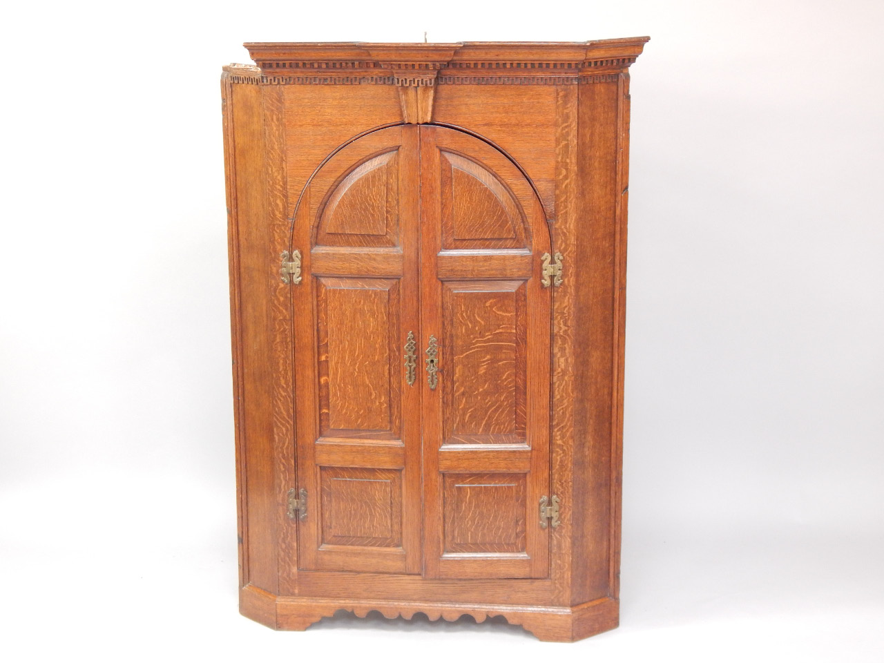 Appraisal: A George III oak hanging corner cupboard the pediment with