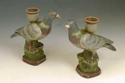 Appraisal: A pair of painted pottery candlesticks modelled as pigeons in