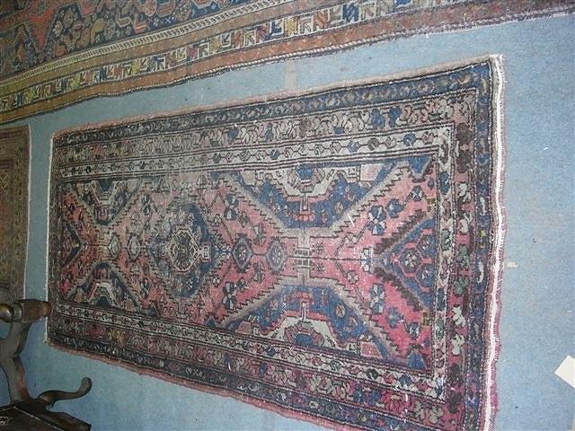 Appraisal: AN HAMADAN RED GROUND RUG with central medallion worn x