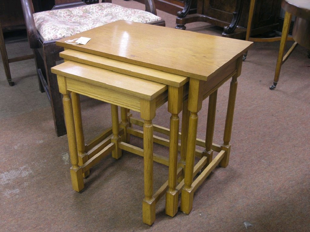 Appraisal: A nest of three solid light oak tables turned underframes