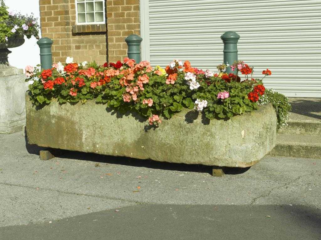 Appraisal: AN ENGLISH ROUGH HEWN SANDSTONE TROUGH with drain hole at