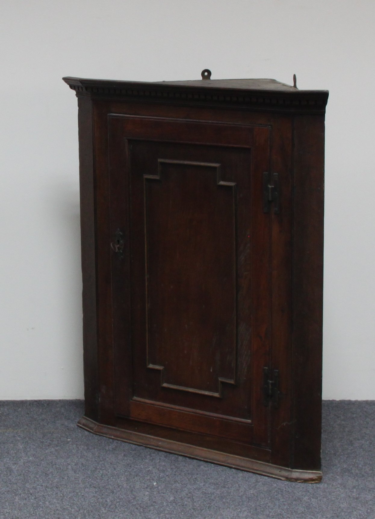 Appraisal: An oak hanging corner cupboard with panelled door