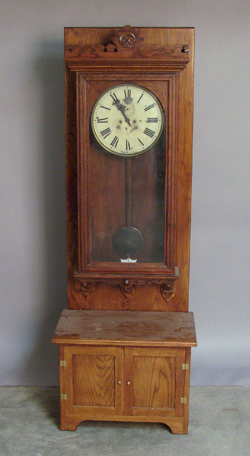 Appraisal: Waterbury oak wall clock mounted on a hall seat h