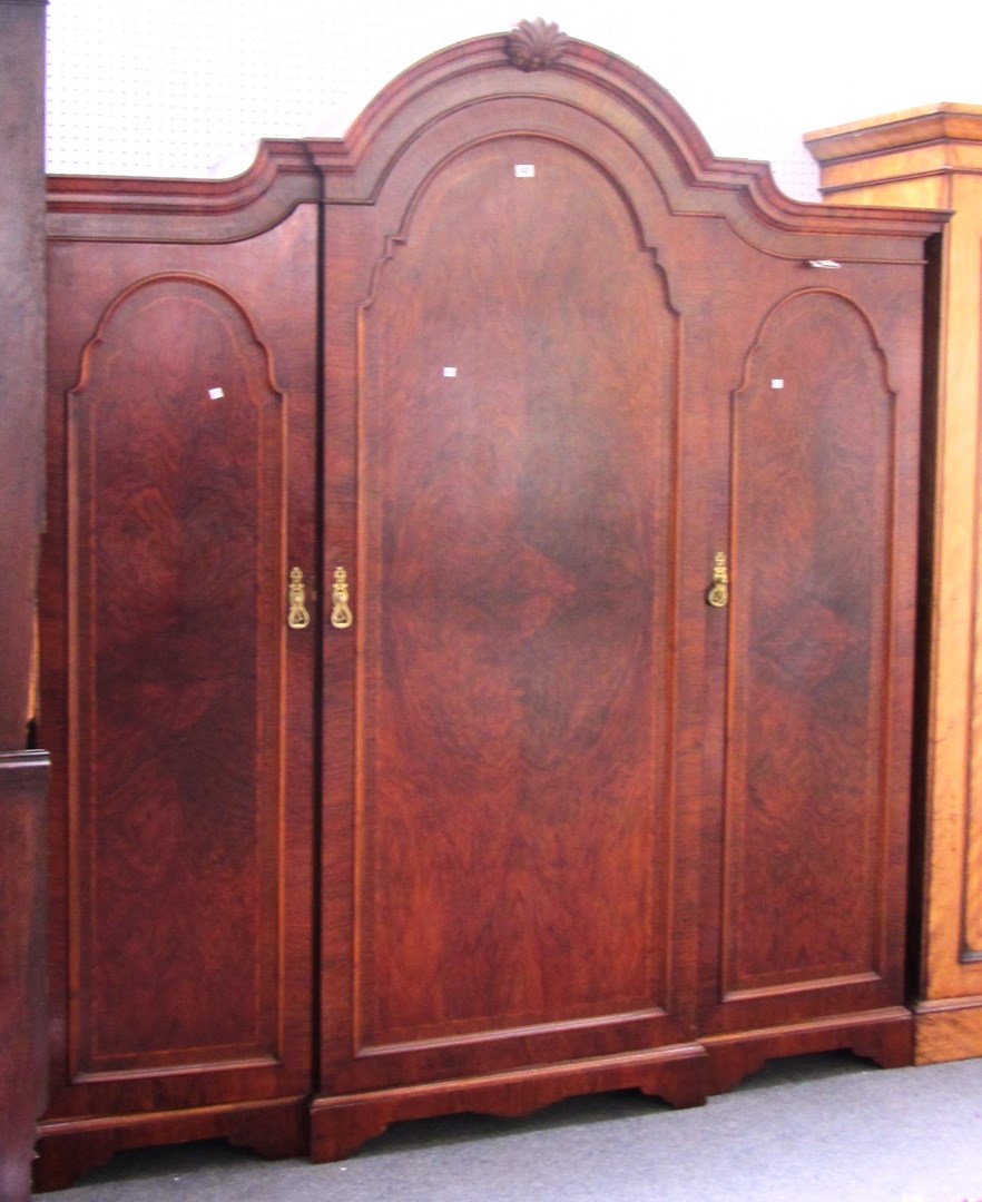 Appraisal: An early th century figured walnut bonnet top triple wardrobe