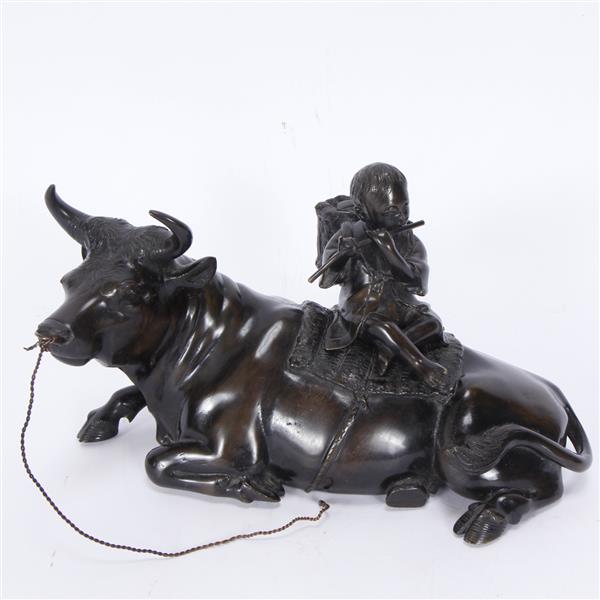 Appraisal: Japanese bronze boy playing flute on recumbent bull figure group