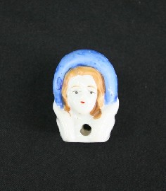 Appraisal: A miniature doll's head with moulded bonnet with red ribbon