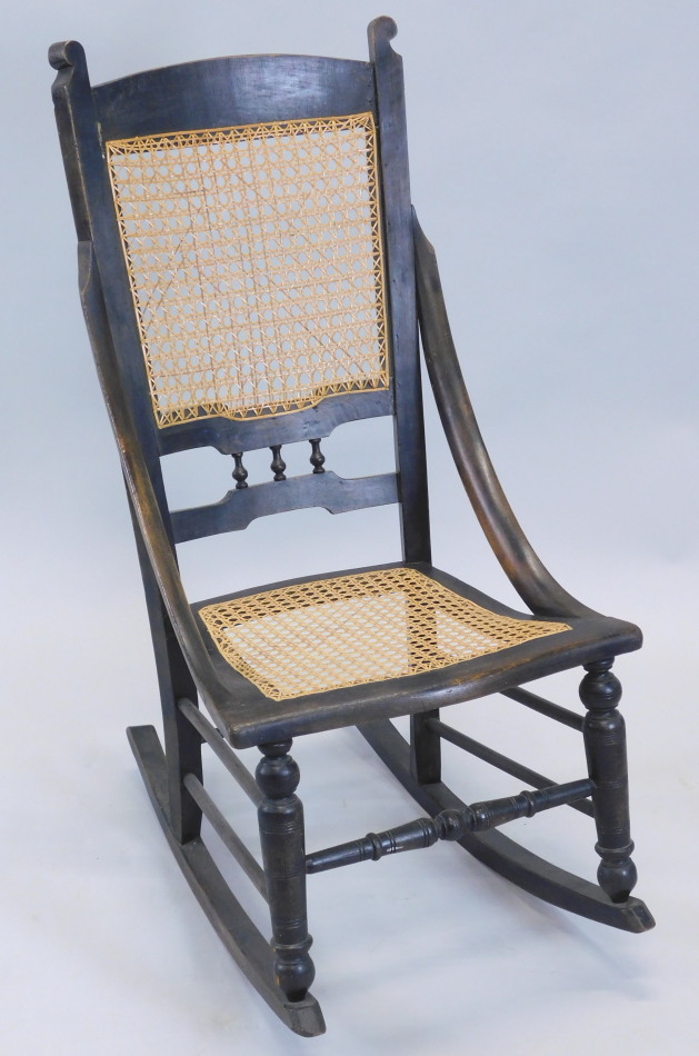 Appraisal: A Victorian ebonised rocking chair with a caned back and