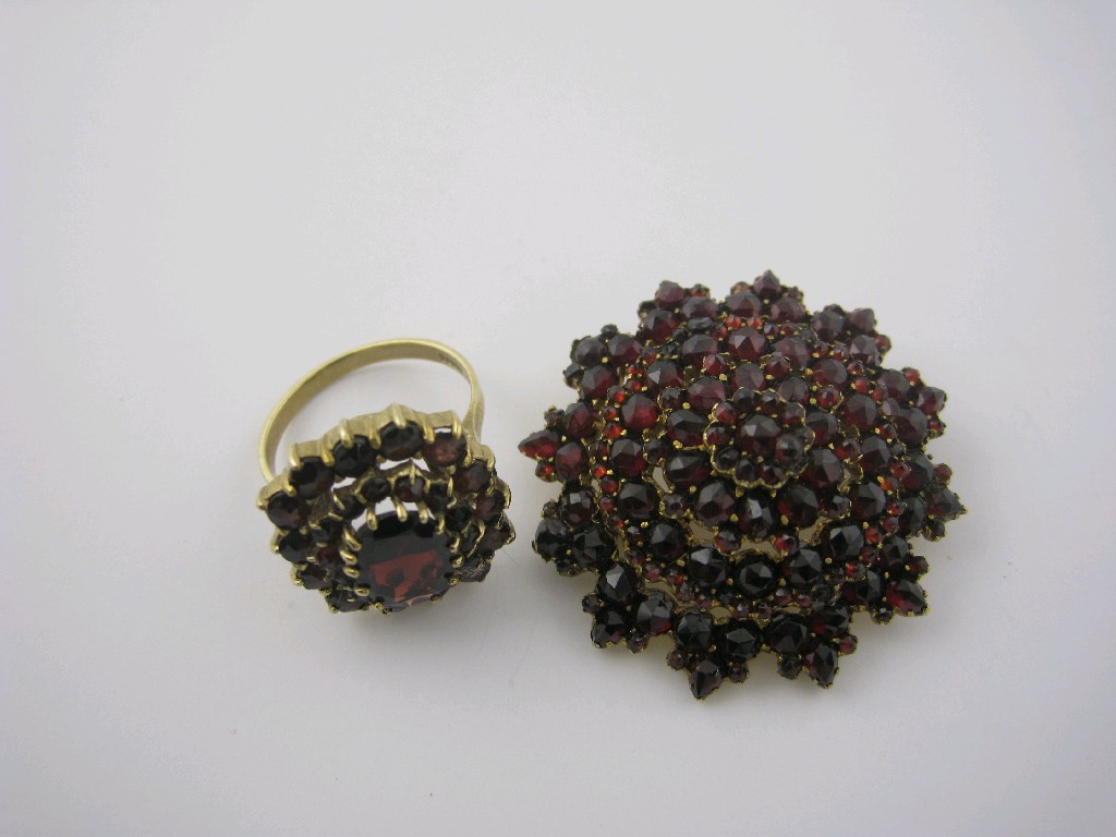 Appraisal: A Garnet Cluster Ring claw-set central oval-cut stone within two