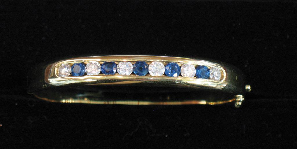 Appraisal: AN CT YELLOW GOLD HINGED BANGLE with a tension-set row