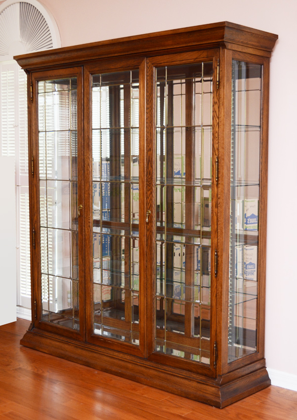 Appraisal: CONTEMPORARY TRIPLE FRONT OAK CURIO CABINET Illuminated interior beveled glass