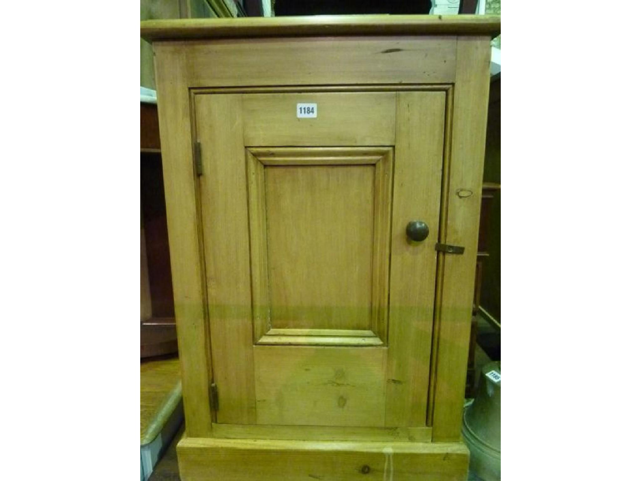 Appraisal: A slender stripped pine side cupboard enclosed by a panelled