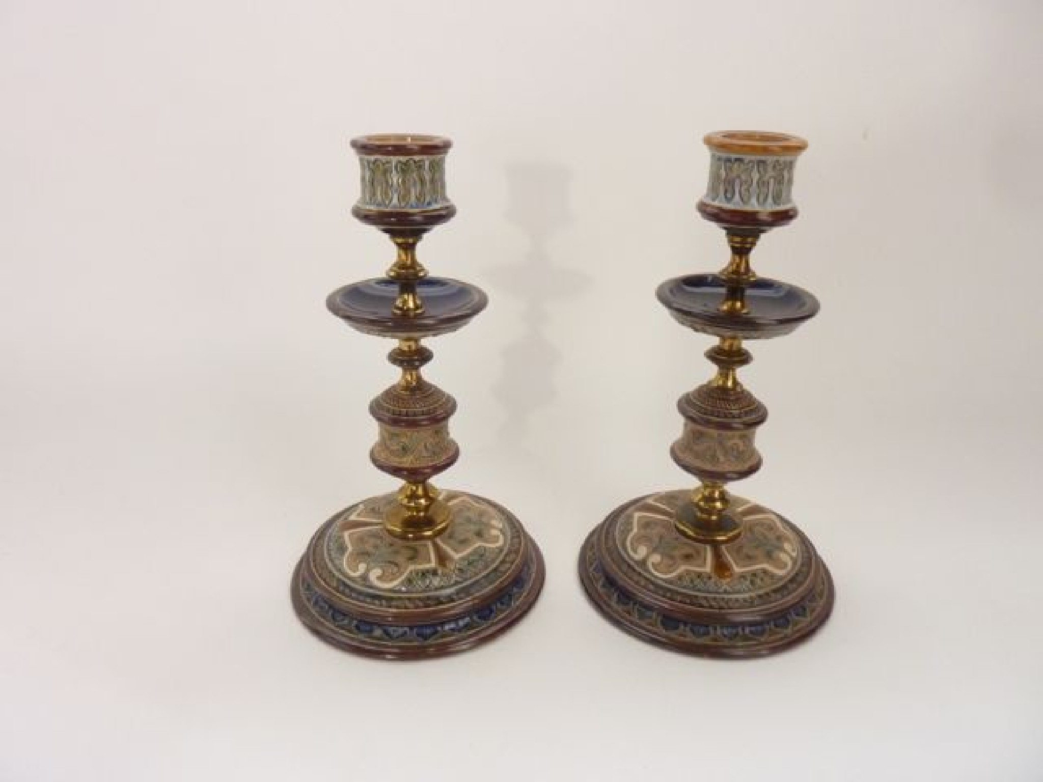 Appraisal: A pair of Doulton Lambeth candlesticks raised on circular bases