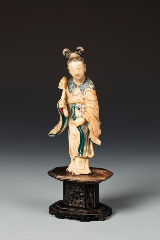 Appraisal: A CHINESE SOAPSTONE FIGURE OF A FEMALE DEITY standing holding