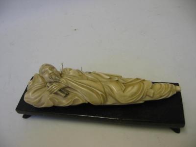 Appraisal: A JAPANESE IVORY OKIMONO c modelled as a reclining gentleman