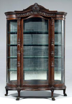 Appraisal: Carved oak curved glass vitrine carved and arched pediment over